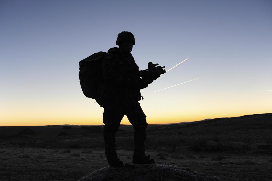 Silhouette of a British army soldier on patrol at sunrise.