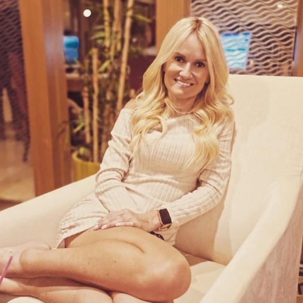 Woman in beige dress sitting in a chair.