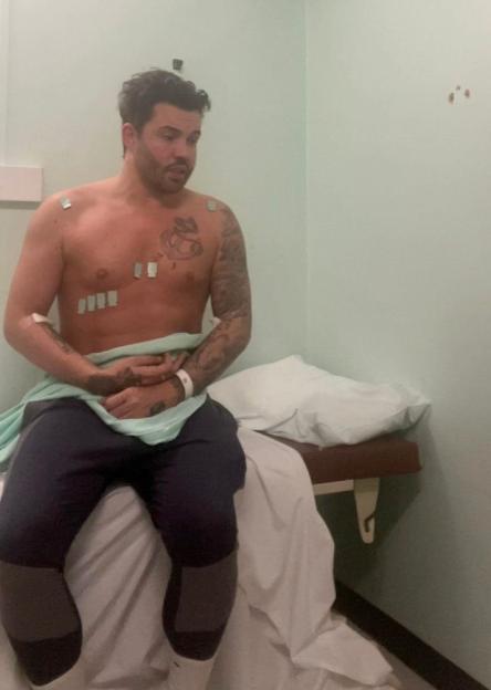 Bobby Norris sitting shirtless on a hospital bed with electrodes on his chest.