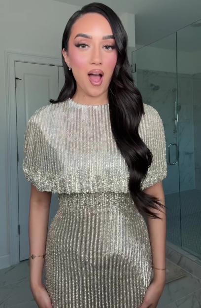 A woman in a beaded silver dress with her mouth open.