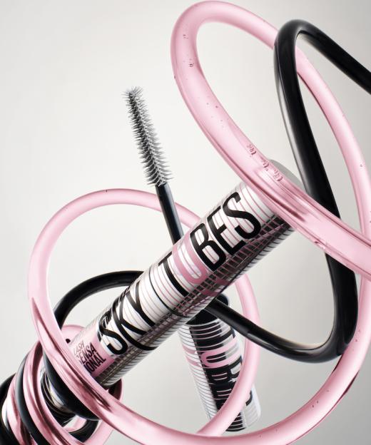 Mascara tube and wand suspended among intertwined pink and black tubing.