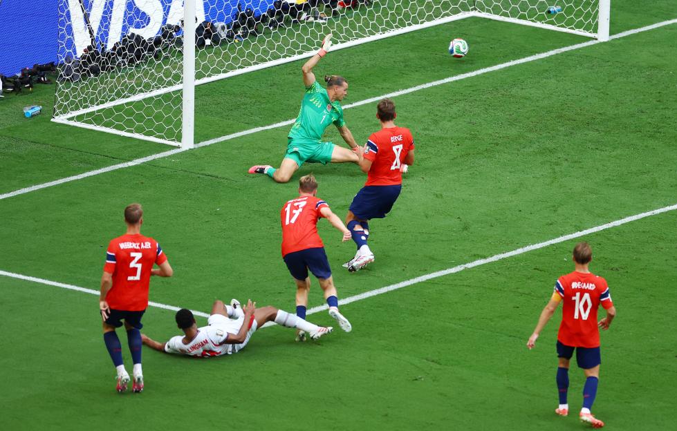 England's Jude Bellingham scores past Norway's Orjan Nyland in a soccer match.