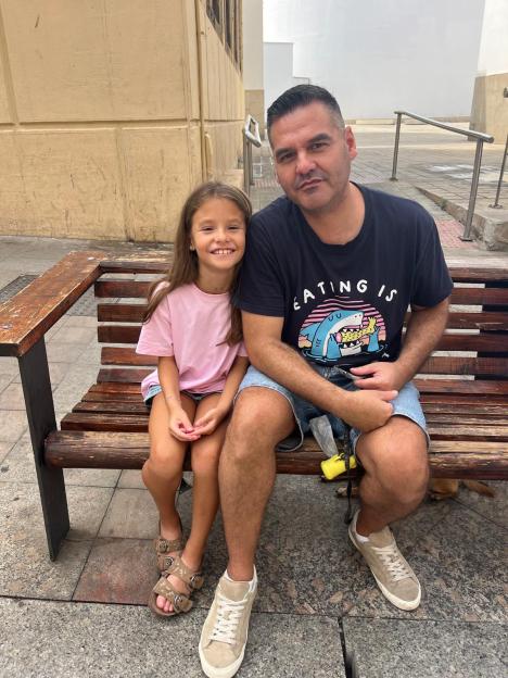 Manu Roman sits on a bench with his daughter Marta.