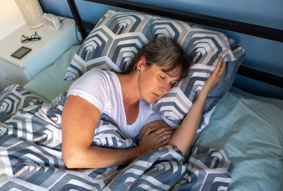 A woman sleeping soundly on her side in bed.