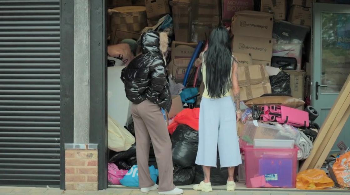 Katie Price and Princess Andre in a cluttered garage overflowing with boxes and belongings.