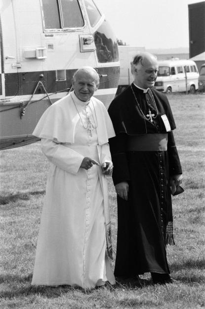 Pope John Paul II walks next to another clergyman.