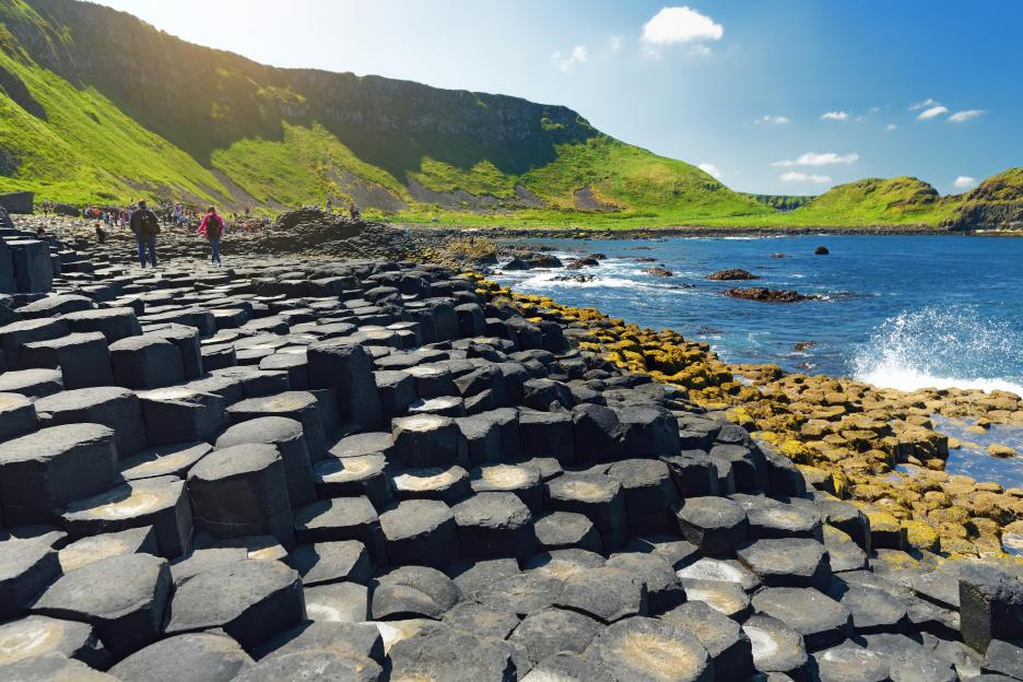 Tourists walking on the hexagonal basalt columns of Giant's Causeway in Northern Ireland.
