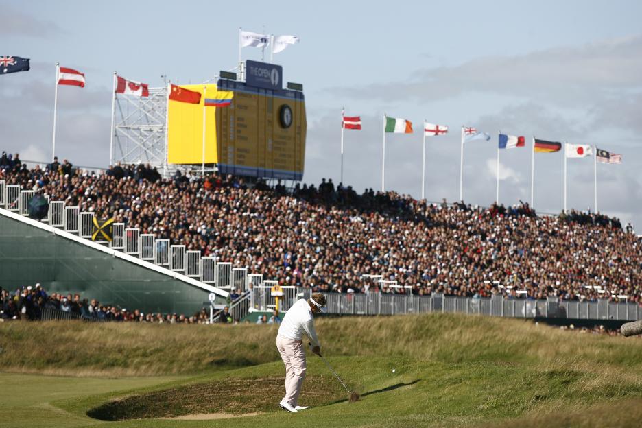 Golfer Ian Poulter chips a golf ball as spectators watch at the Open Championship.