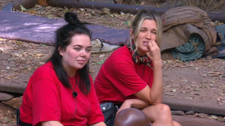 Two women in red shirts sitting outdoors.