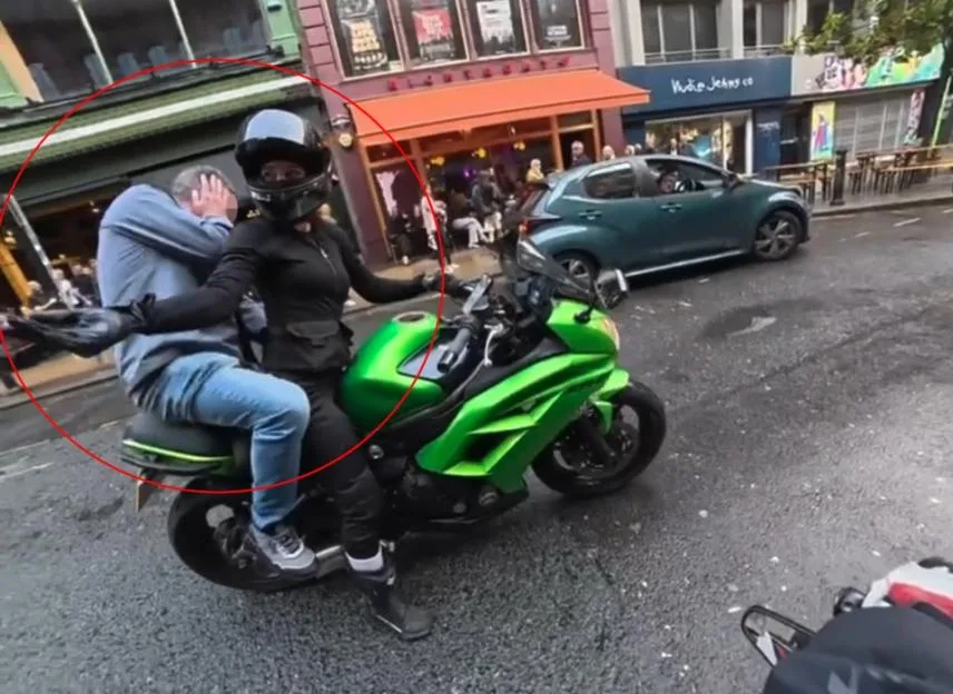 VIDEO: Motorcycle rider smacks 'inappropriate' old man jumping onto bike and grabbing her hips while she's sitting in traffic