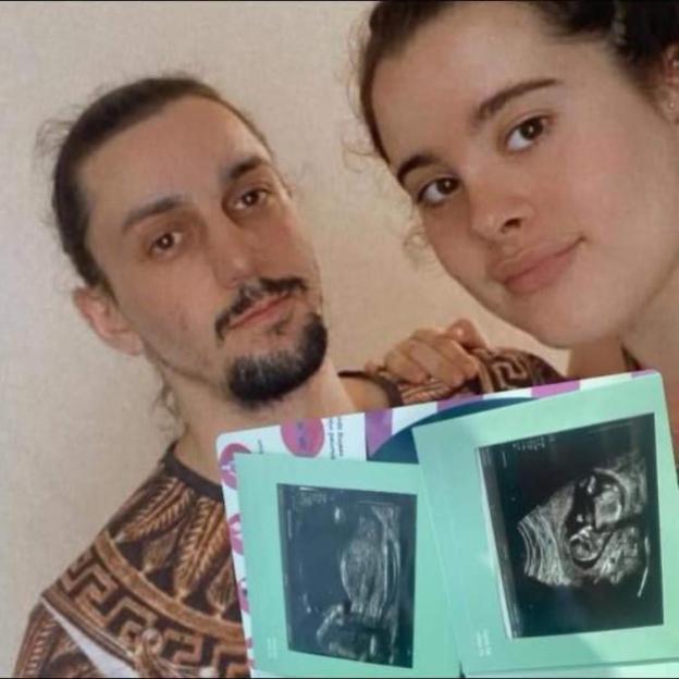 A man and a woman holding up two ultrasound images.