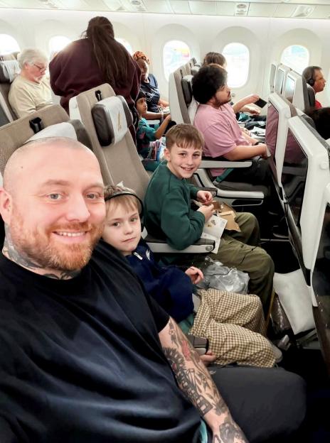 Joseph Oxley and his two sons pose for a selfie on an airplane.