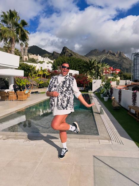 David Potts poses by a swimming pool with mountains in the background.