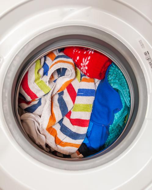 Washing machine drum overflowing with colorful clothes and towels.
