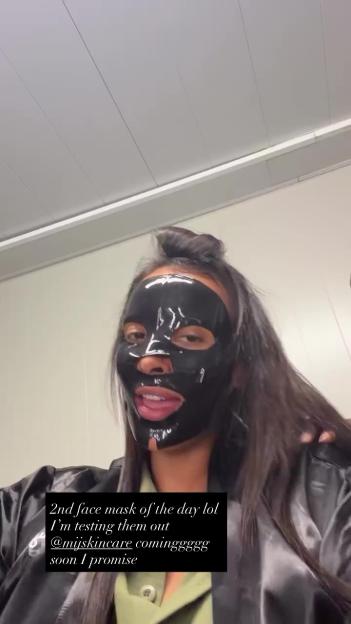 Maya Jama wearing a black face mask, with a text overlay about it being her second face mask of the day and her testing products for @mijskincare.