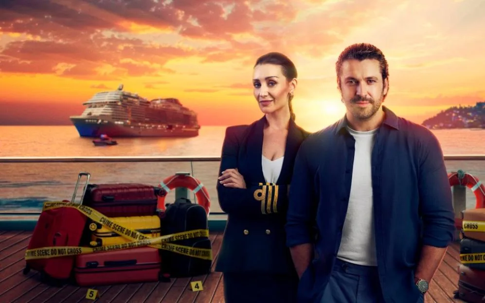 Catherine Tyldesley as Kate and Shayne Ward as Jack stand on a cruise ship deck at sunset, with a stack of luggage wrapped in crime scene tape beside them.