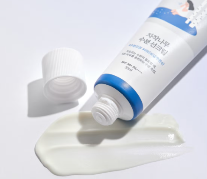 A tube of Round Lab SPF cream with its white cap off and cream squeezed out, showing its texture.