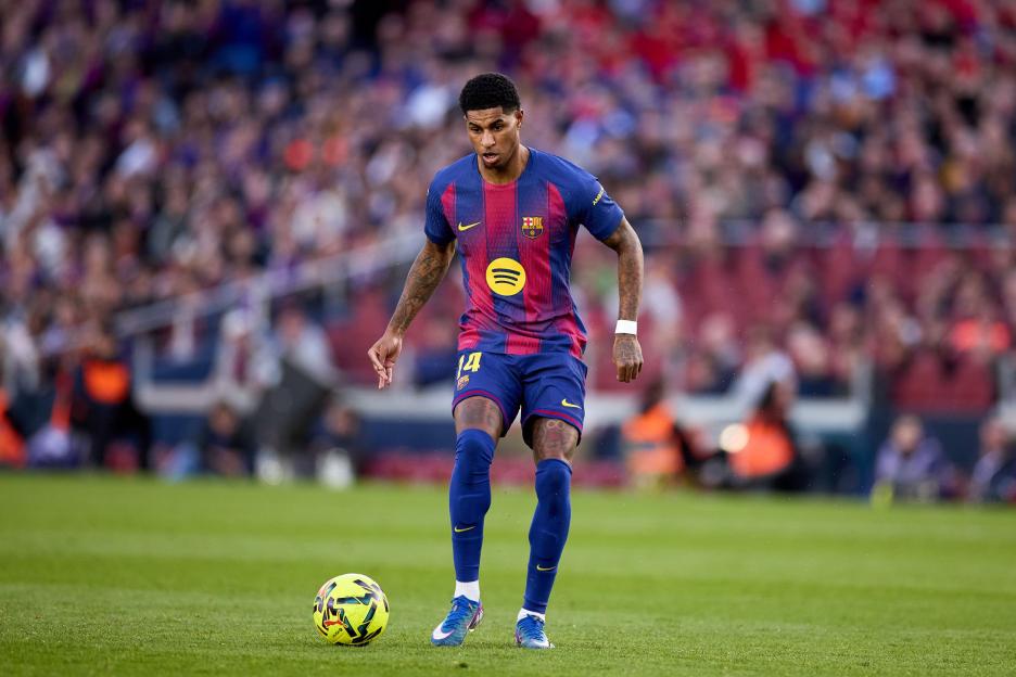 A soccer player in a blue and red striped jersey dribbles a yellow and green ball.