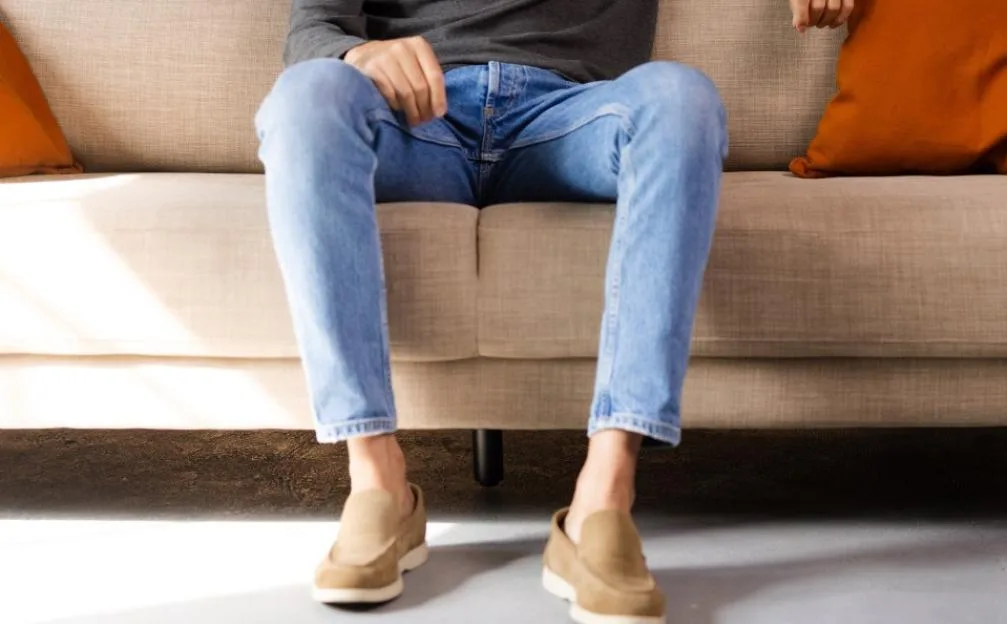 Young adult man relaxing on a sofa, looking at camera and smiling