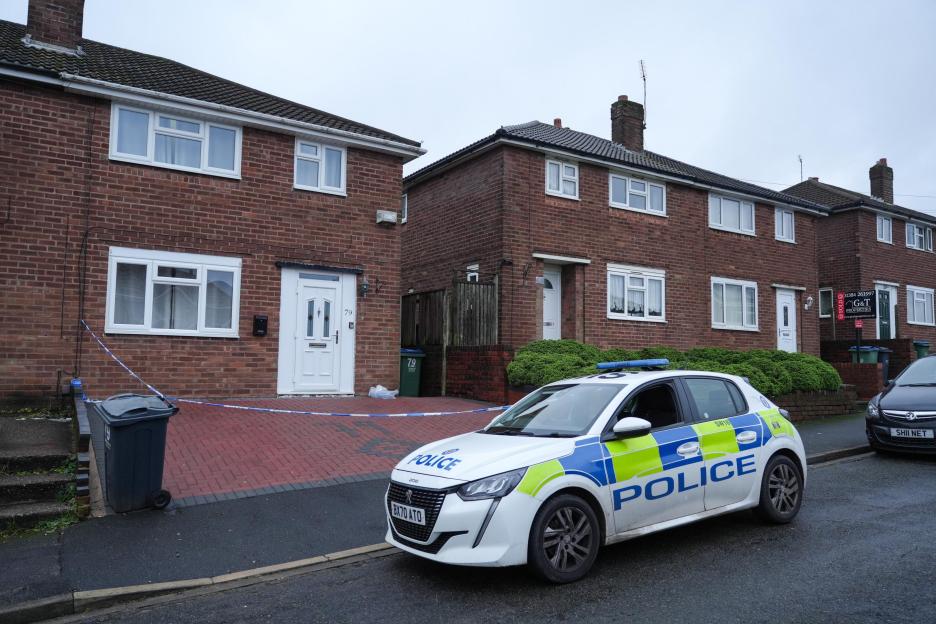 Police car with blue and white crime scene tape outside a house where a woman was found unresponsive.