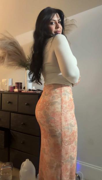 Lizette Watson posing while wearing a white shirt and a patterned maxi skirt.