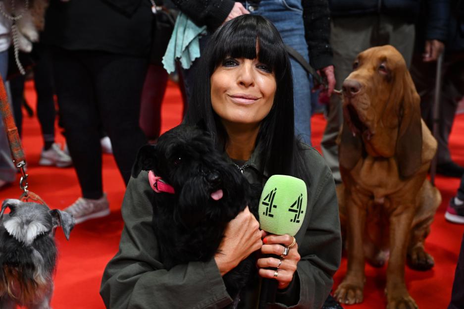 Claudia Winkleman poses with a small black dog and a Channel 4 microphone at Crufts 2026.