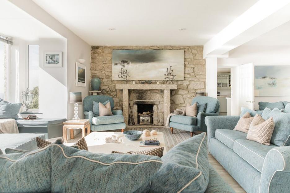 Living room with blue sofas, armchairs, and a stone fireplace.