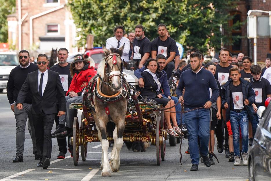 Mourners accompanying a horse-drawn carriage carrying the coffin of Rico Burton to his funeral.