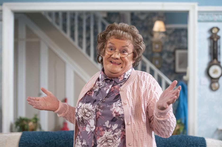 Agnes Brown (Brendan O'Carroll) from Mrs. Brown's Boys smiling with arms outstretched.
