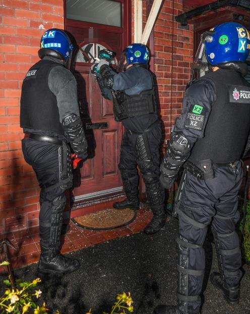 Two Greater Manchester Police officers breaking down a door during a raid.