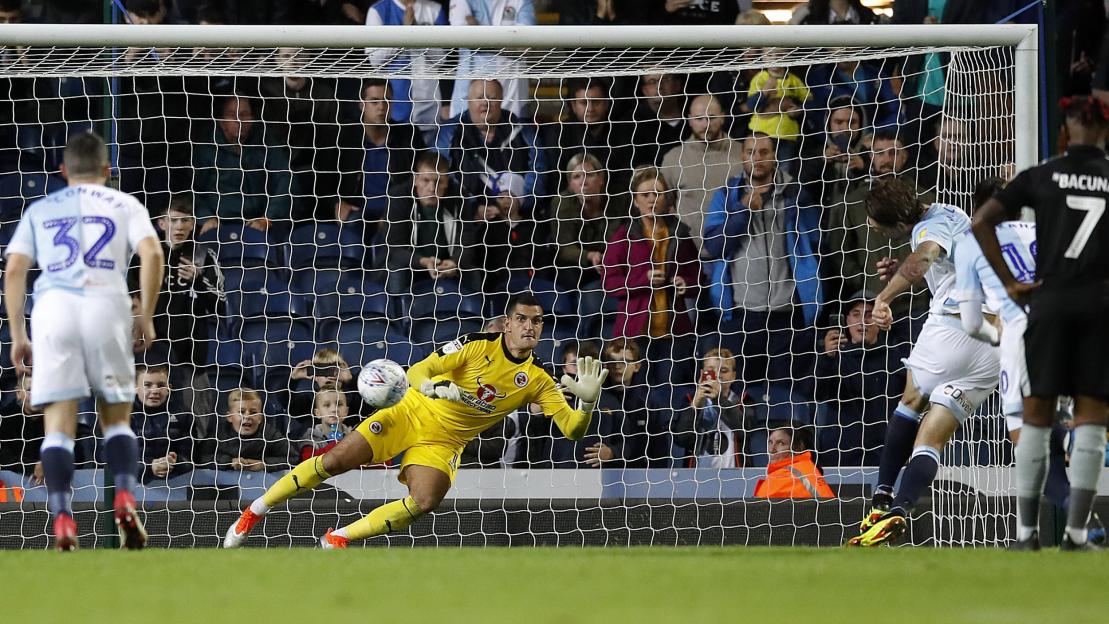 Soccer player attempting a penalty kick while the goalkeeper dives to block it.