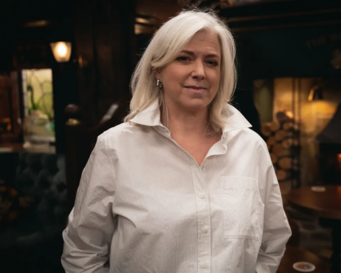 A woman with shoulder-length blonde hair and a white striped shirt.