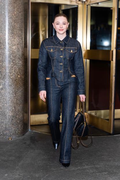 Chloe Grace Moretz wearing a dark blue denim jacket and matching jeans.