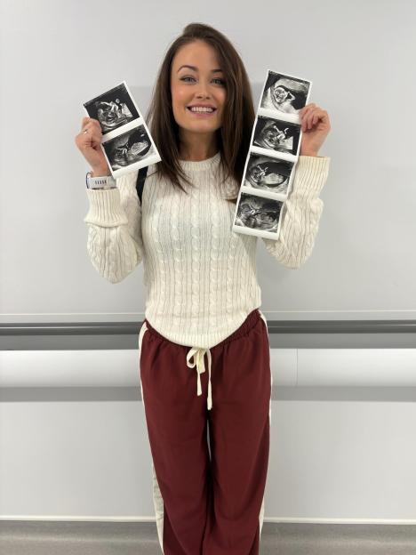 Jess Impiazzi smiling and holding up two strips of ultrasound images.