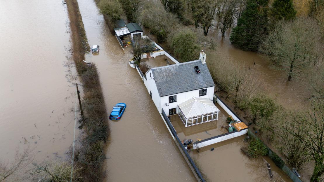 Aerial view of cars stuck in floodwaters around a house in Weycroft, Axminster, England.