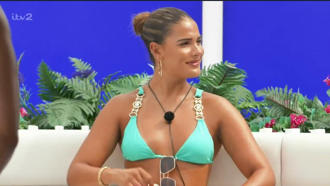 Woman in a teal bikini sitting on a white sofa.