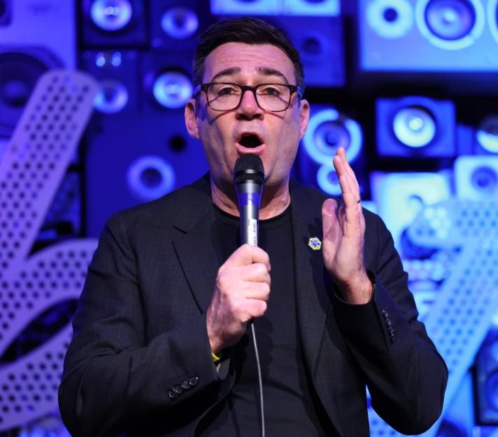 Mayor Andy Burnham speaking into a microphone.