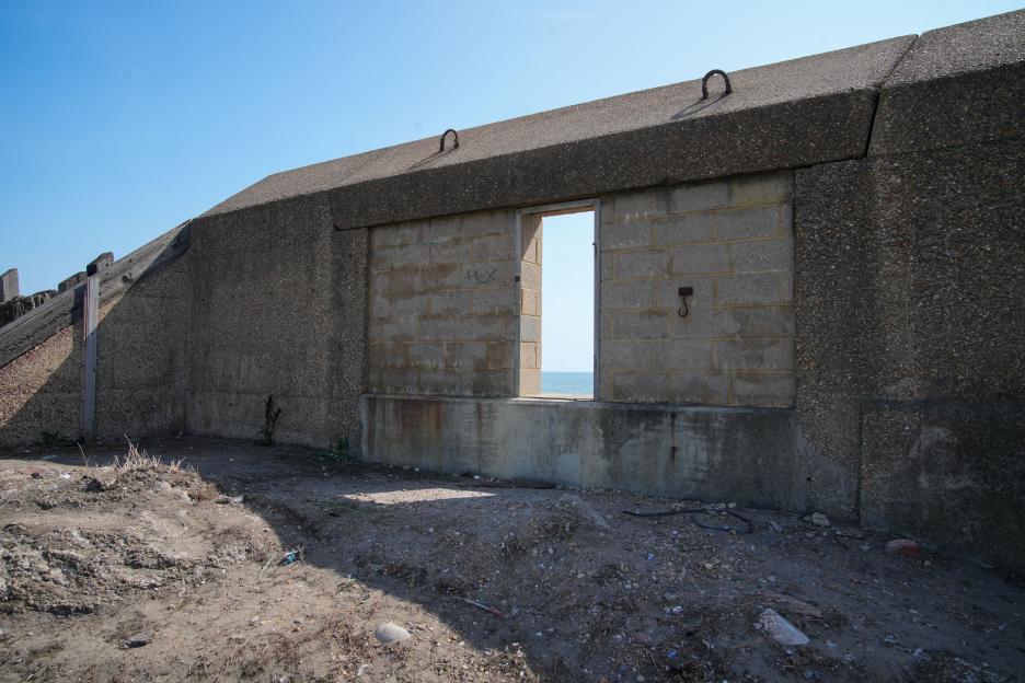 A gap in a concrete wall reveals the ocean.
