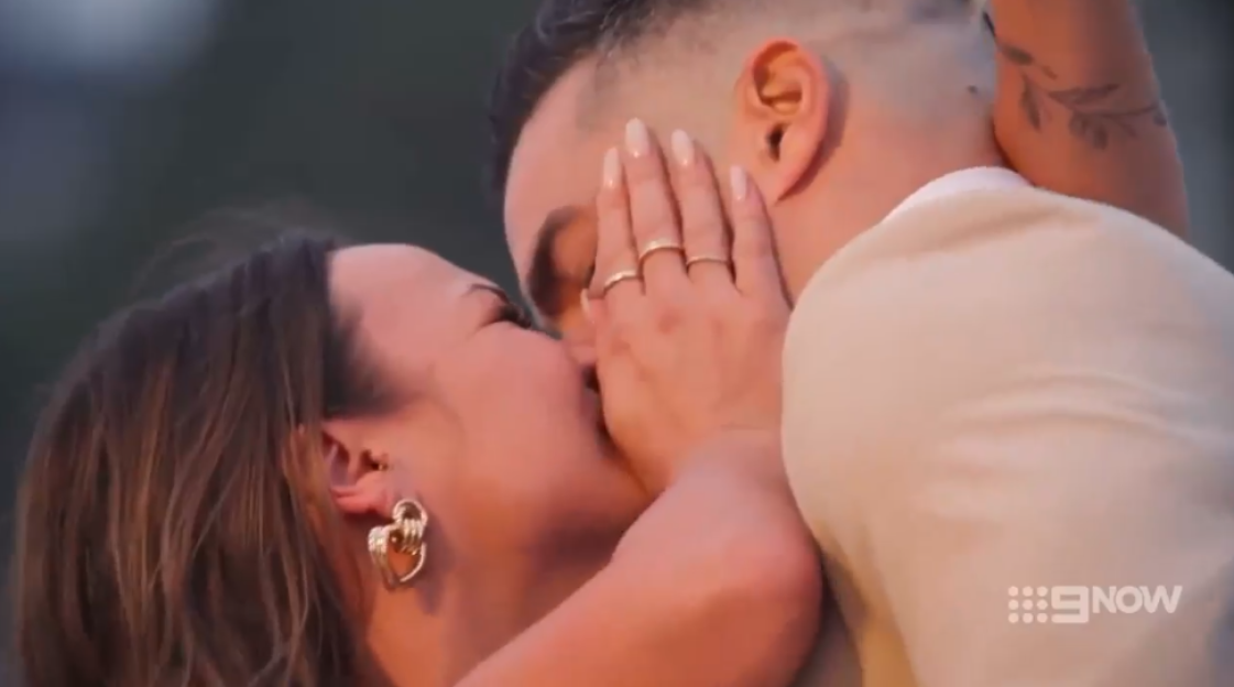 A couple embracing and kissing, with the woman's hand resting on the man's face.