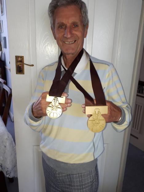 Nick Joseph smiling while wearing two gold medals around his neck.