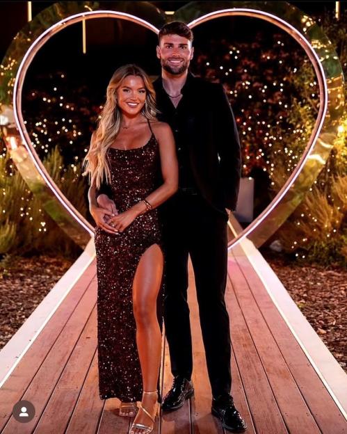 Molly Smith and Tom Clare posing in front of a large heart-shaped archway.