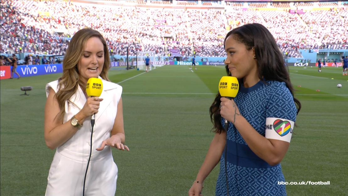 Alex Scott wearing a OneLove armband in a stadium with another commentator.