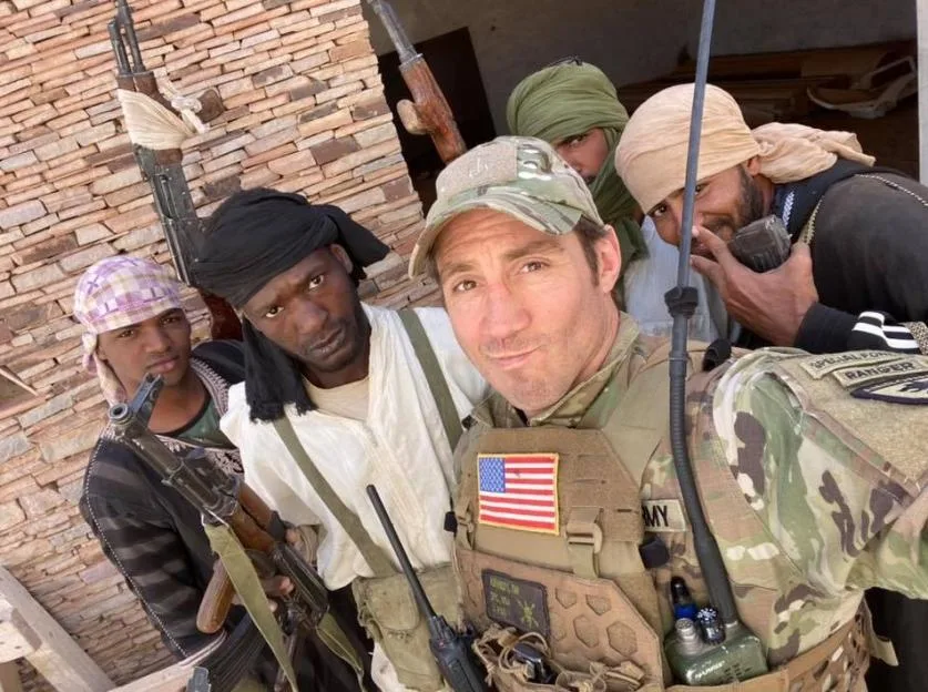 Tim Kennedy in military uniform taking a selfie with armed local men.