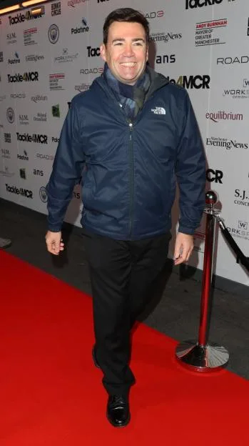 Mayor of Manchester Andy Burnham smiles on a red carpet at a charity dinner.