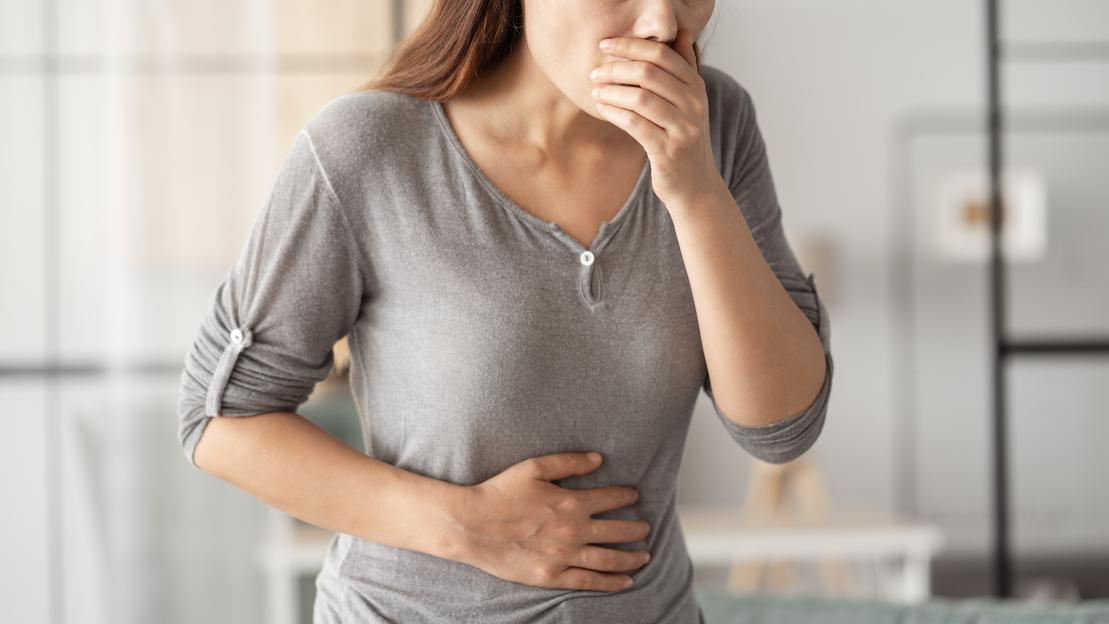 Woman holding her stomach and mouth due to nausea.