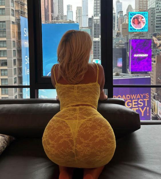 a woman in a yellow lace dress looks out a window at broadway 's gest city