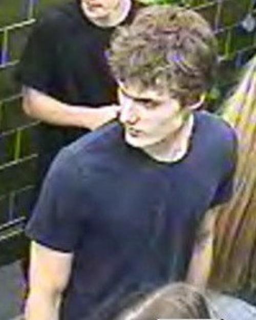 A young man with curly brown hair in a dark blue t-shirt.
