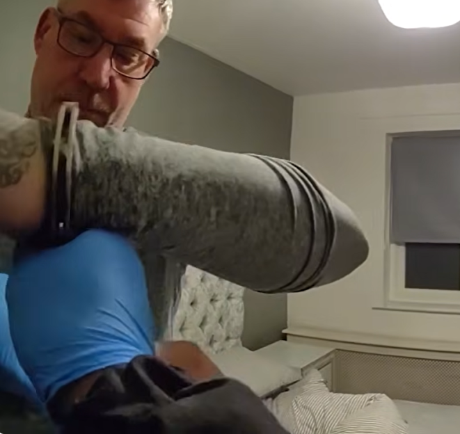 Man in glasses putting on blue medical gloves.