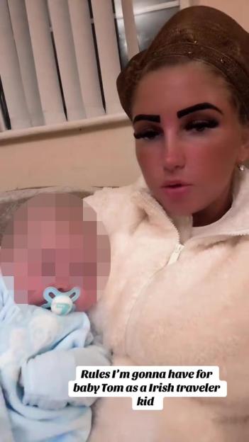 A woman in a cream jacket and a brown head covering holding a baby with a pacifier.