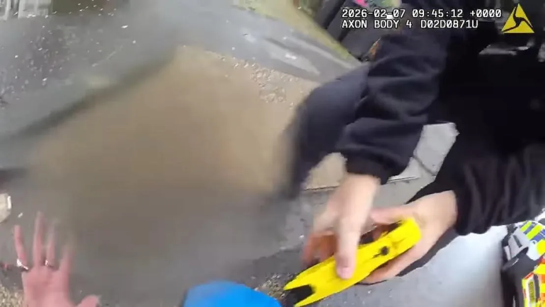 Body-worn camera footage showing a police officer holding a Taser while approaching a suspect.